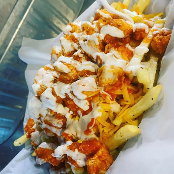 Southern-style fries topped with crispy chicken, shredded cheese, and a creamy white sauce.