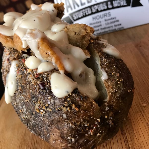 A southern-style baked potato topped with crispy fried chicken and creamy white gravy.