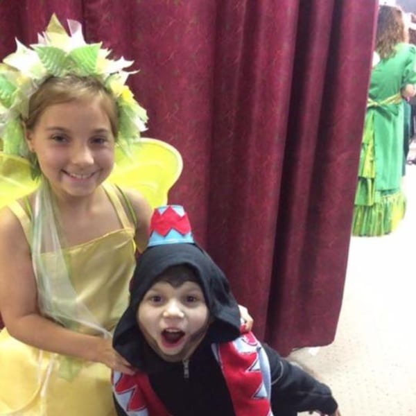 Two children in costumes, one in a green fairy outfit and the other in a black and red costume.