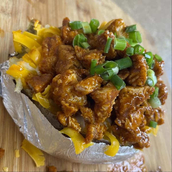 A southern-style baked potato, loaded with saucy chicken, melted cheese, and green onions.