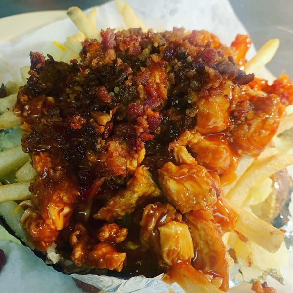 Southern-style fries loaded with chicken, bacon bits, and a generous drizzle of sauce.
